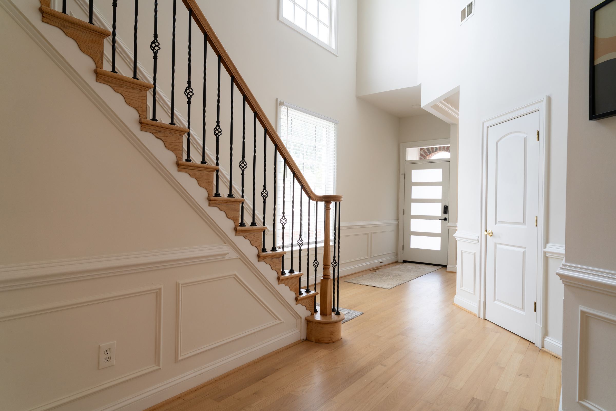 Two story foyer with oak staircase and raised panel wainscoting