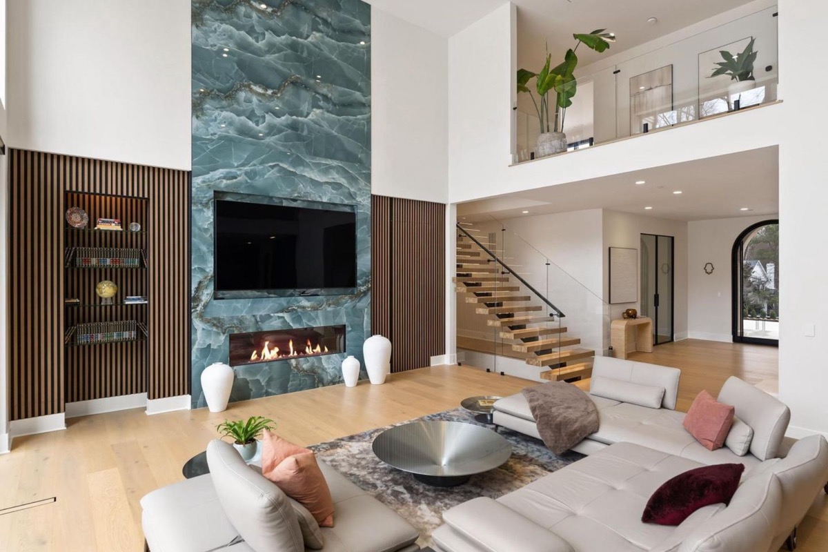 Great room with stone fireplace wall, slatted millwork and a floating staircase