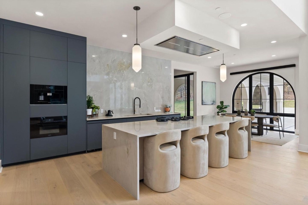 Kitchen with navy cabinetry, marble waterfall island and arched steel windows